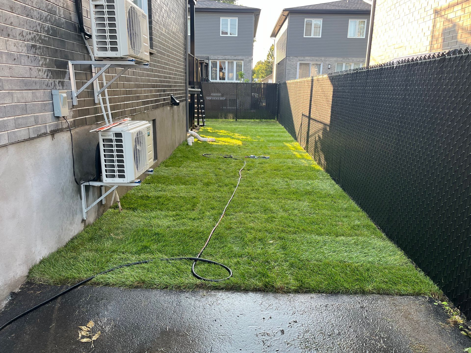 A backyard with a lot of grass and a fence.
