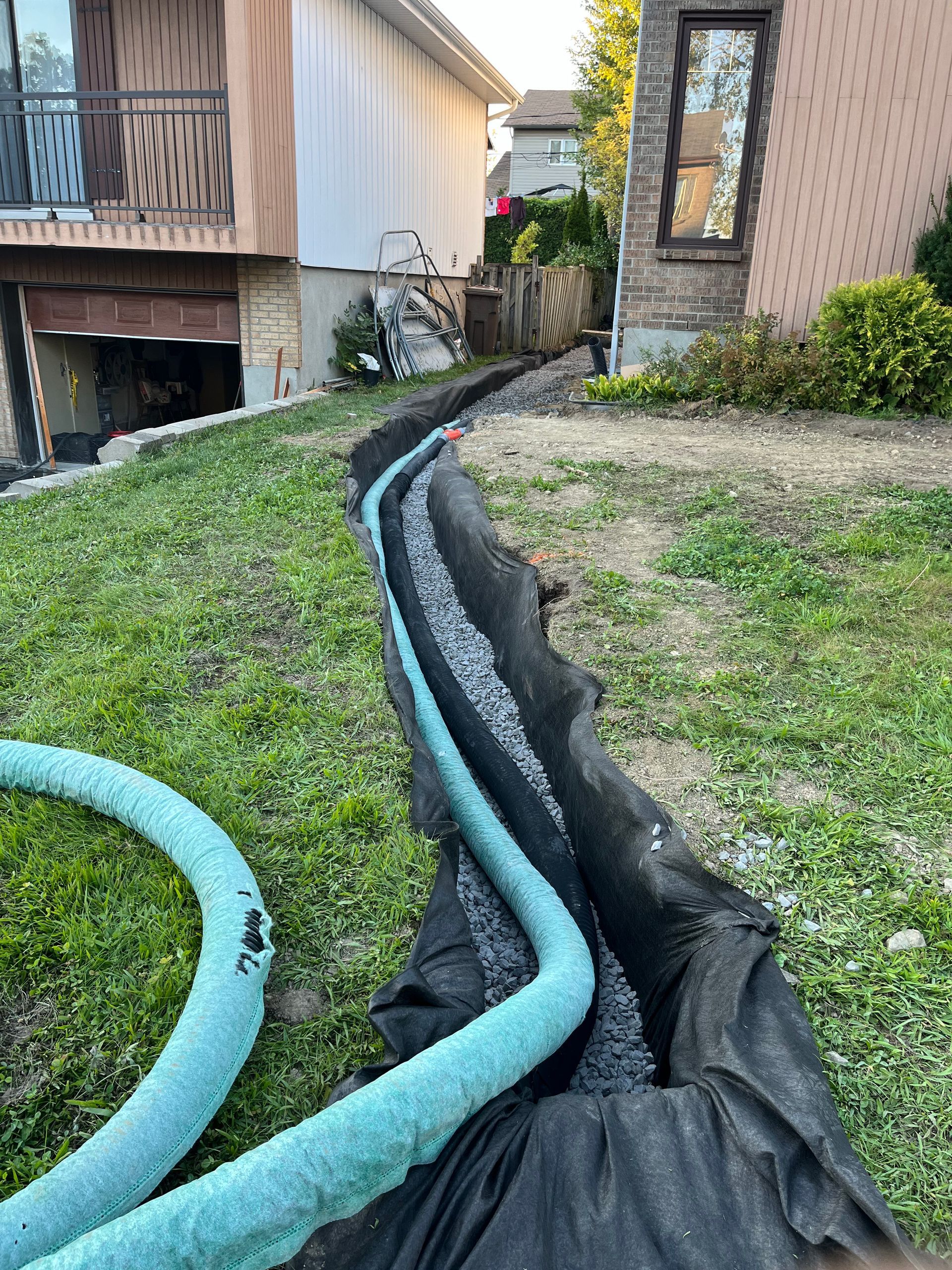 A hose is laying in the grass in front of a house.