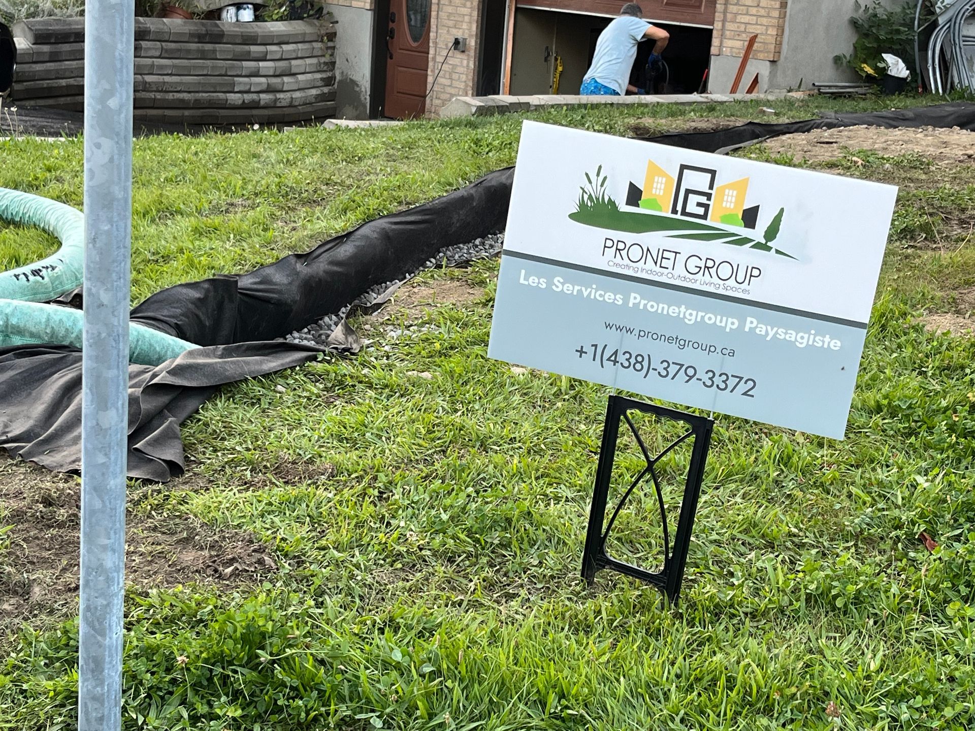 A sign is sitting in the grass in front of a house.