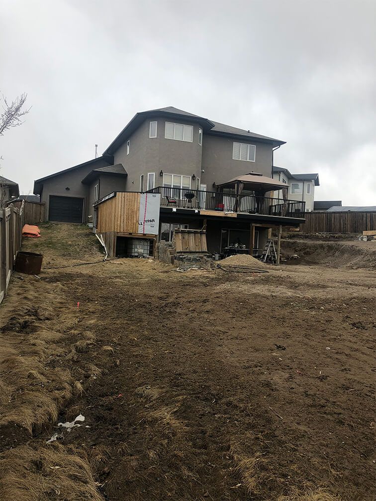 A large house is sitting on top of a dirt hill.