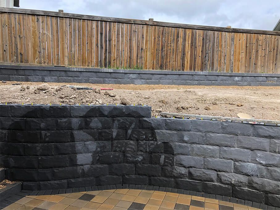 A brick wall with a wooden fence in the background.
