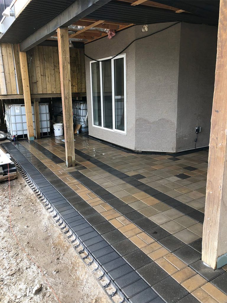 A brick walkway leading to a house under construction.