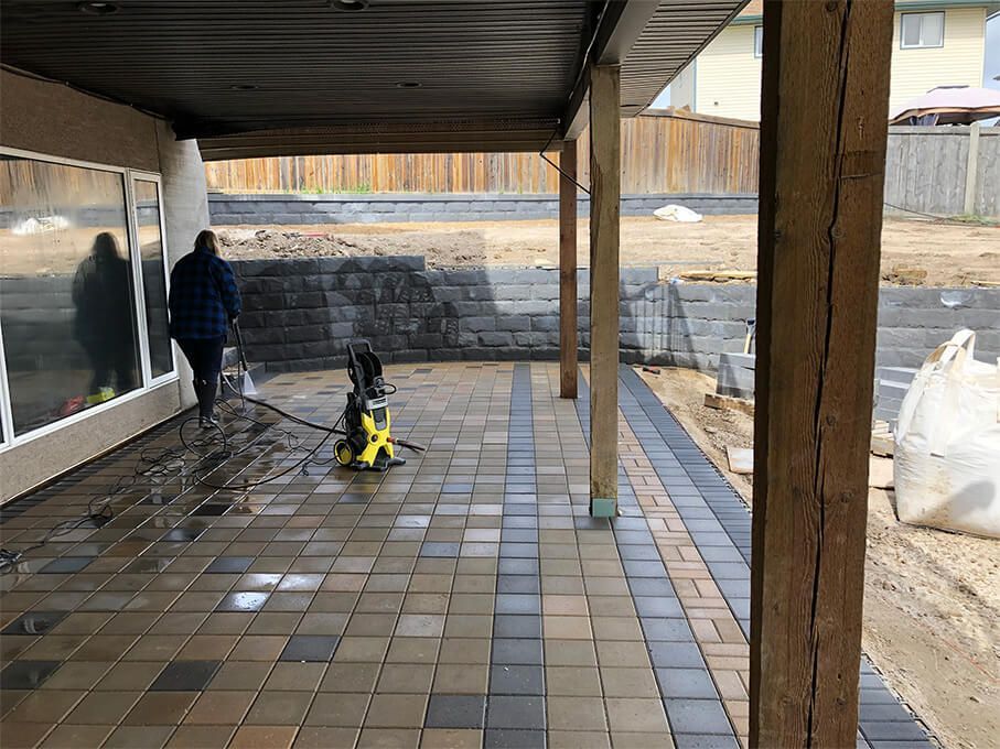 A man is cleaning a patio with a machine.