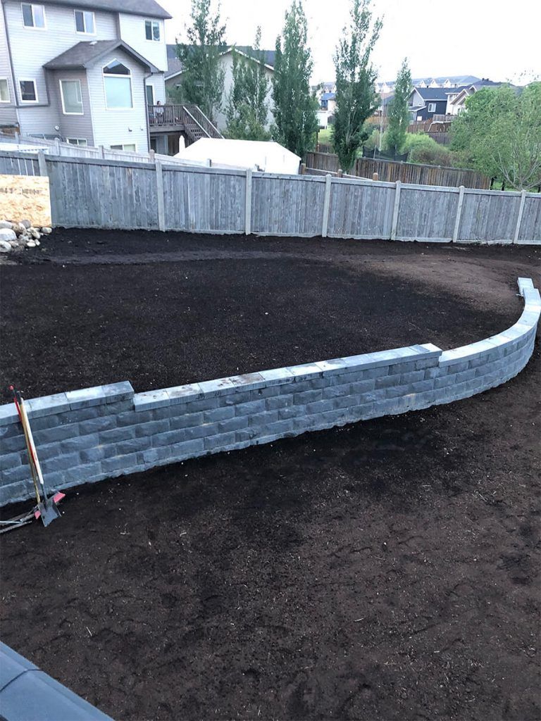 A backyard with a fence and a brick wall