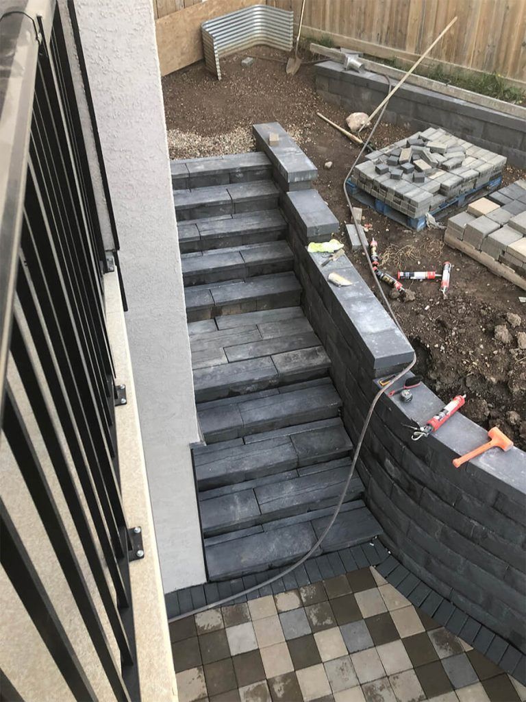 A staircase is being built in a backyard next to a wall.