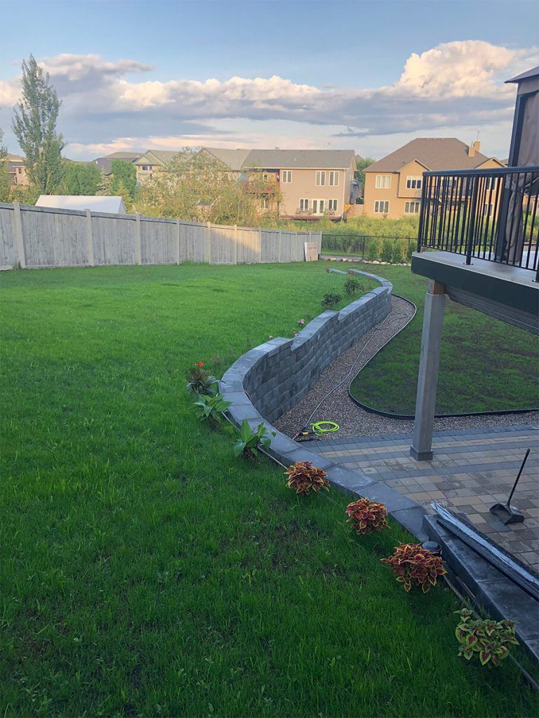 A lush green backyard with a deck and a fence.
