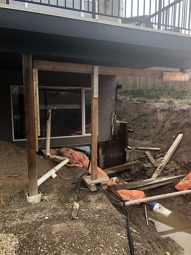 A man is laying on the ground in front of a house under construction.