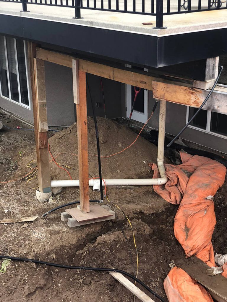 A house is being built with a deck being built underneath it.