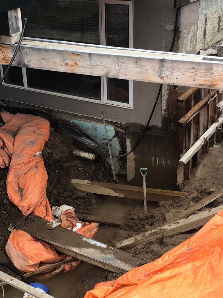 A construction site with a house in the background and a tarp on the ground.
