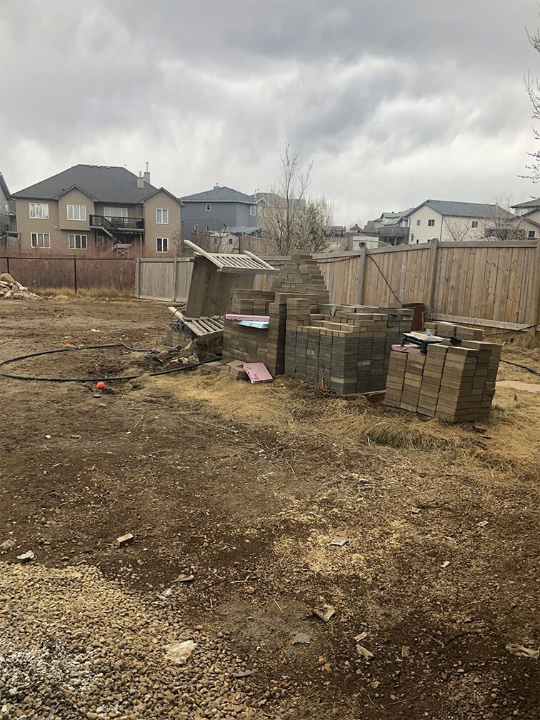 There are a lot of bricks in the dirt in the backyard.