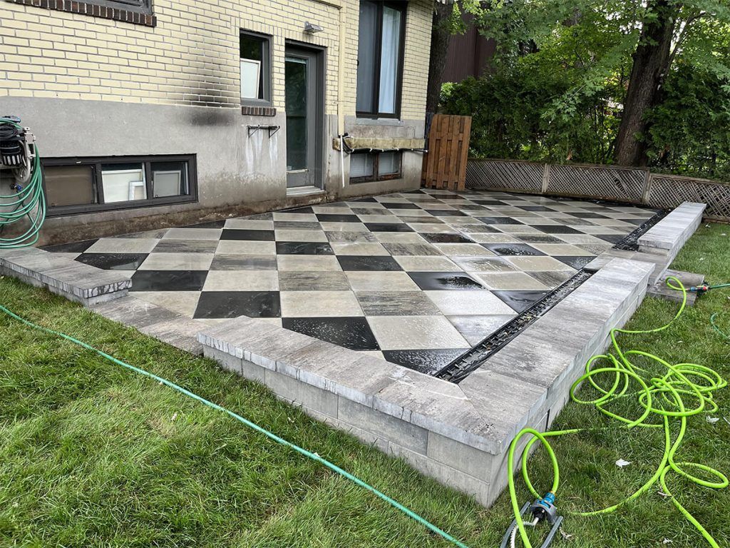 A patio with a checkered pattern is being built in front of a house.