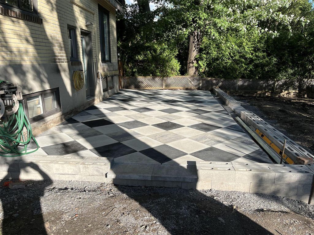 A checkered patio is being built in front of a house.