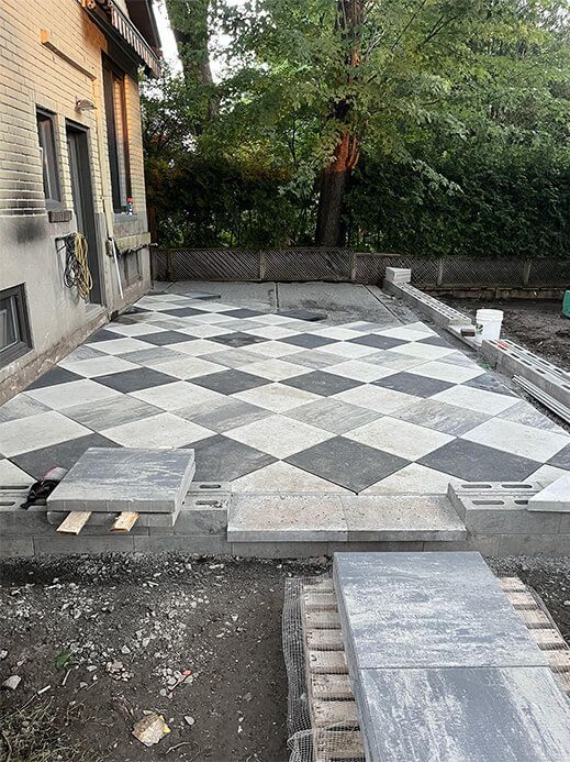 A black and white checkered patio is being built in front of a house.