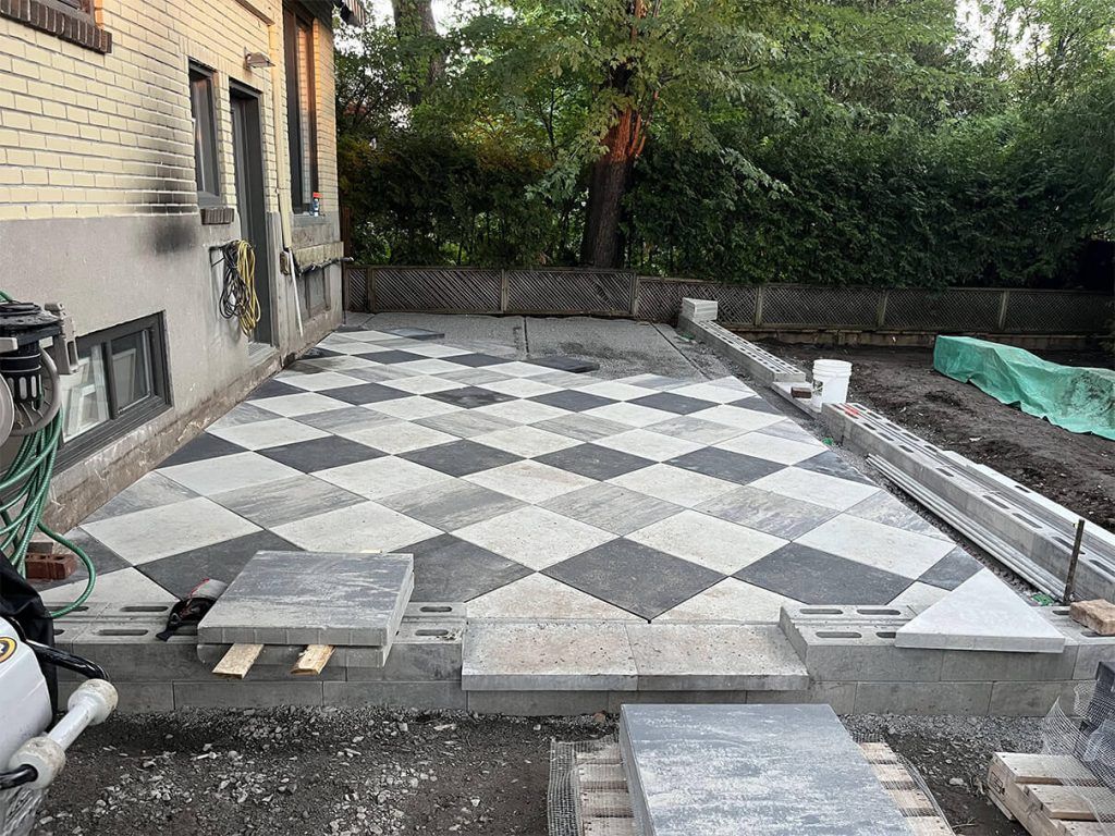 A black and white checkered patio is being built in front of a house.