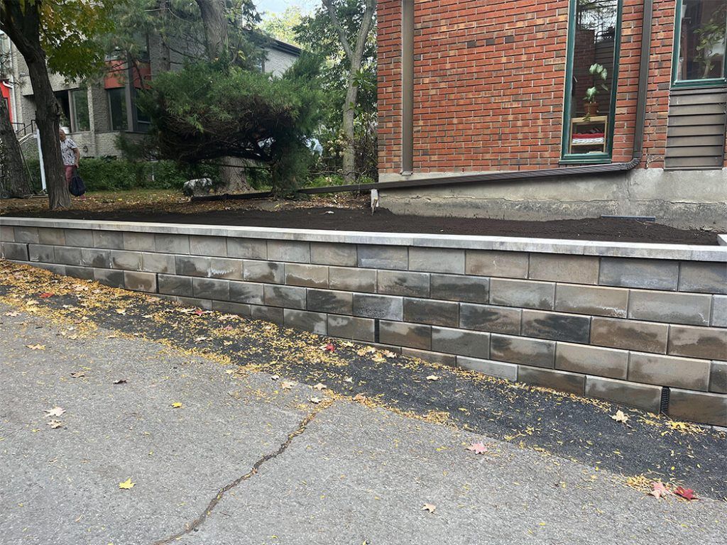A brick wall is being built in front of a brick house.