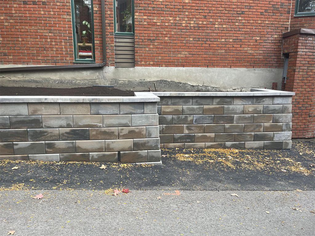 A brick wall is being built in front of a brick building