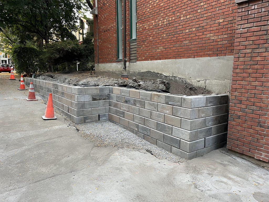 A brick wall is being built in front of a brick building