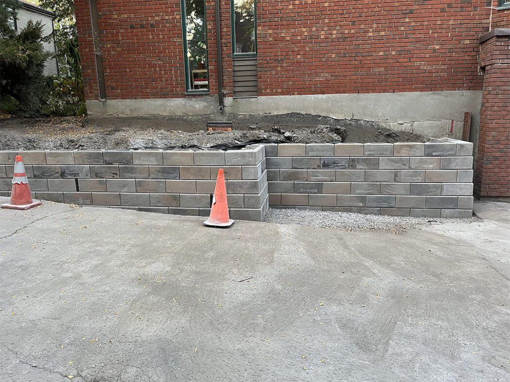A brick wall is being built in front of a brick building