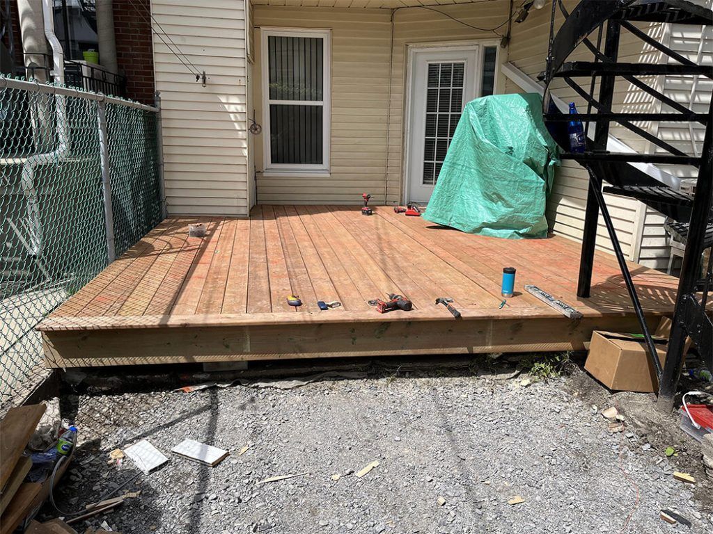 A wooden deck is being built in the backyard of a house.