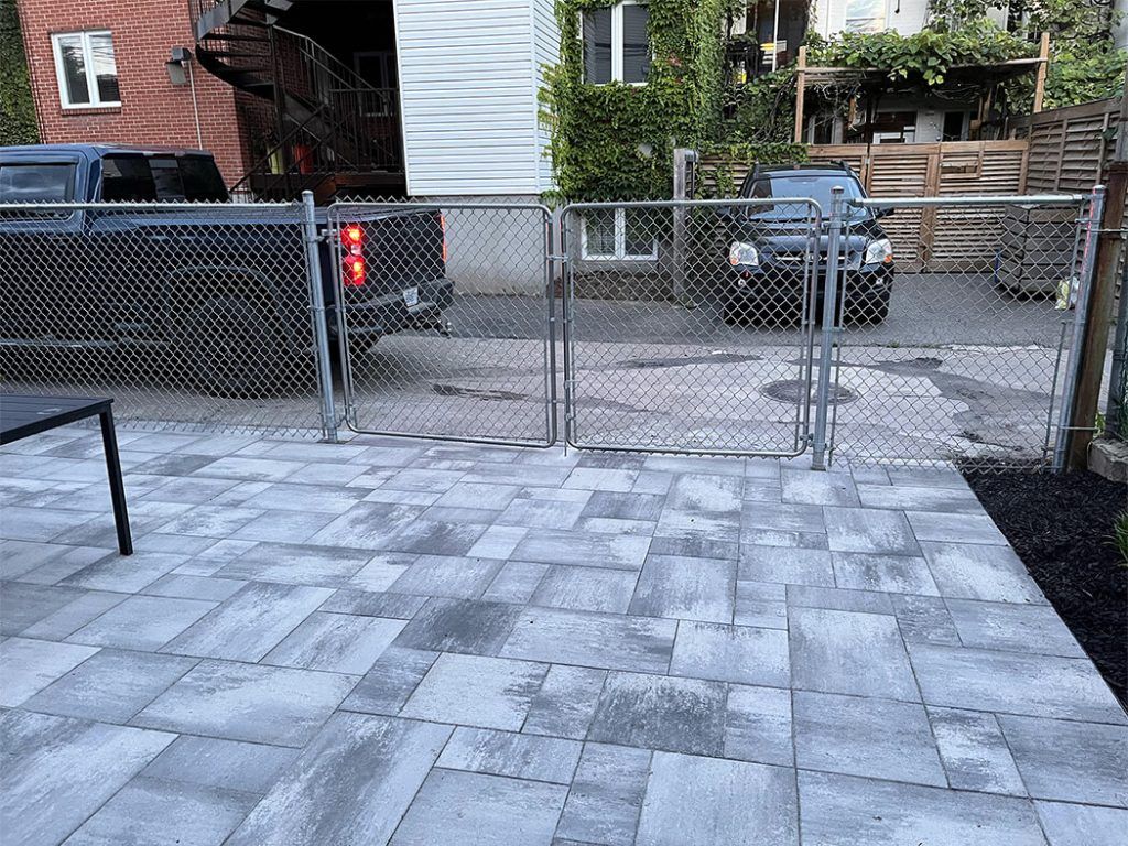 A patio with a chain link fence and a truck parked in the background.