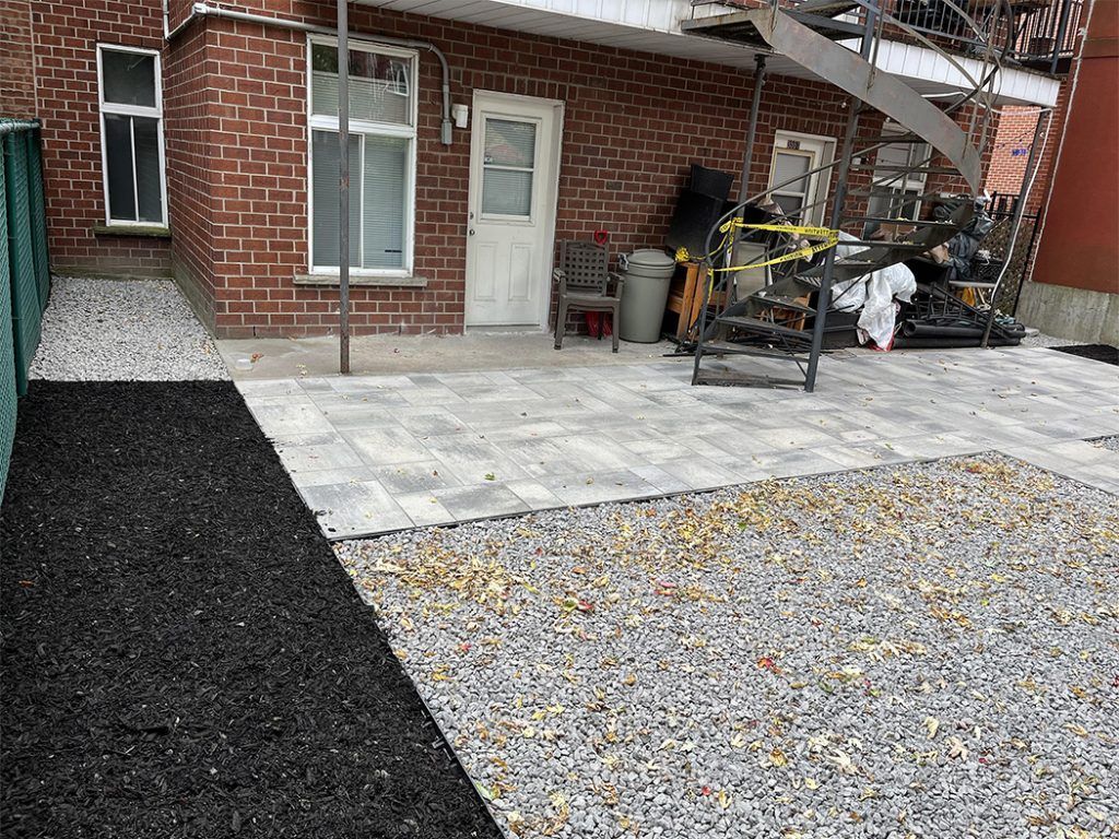 A brick building with a patio and gravel in front of it.