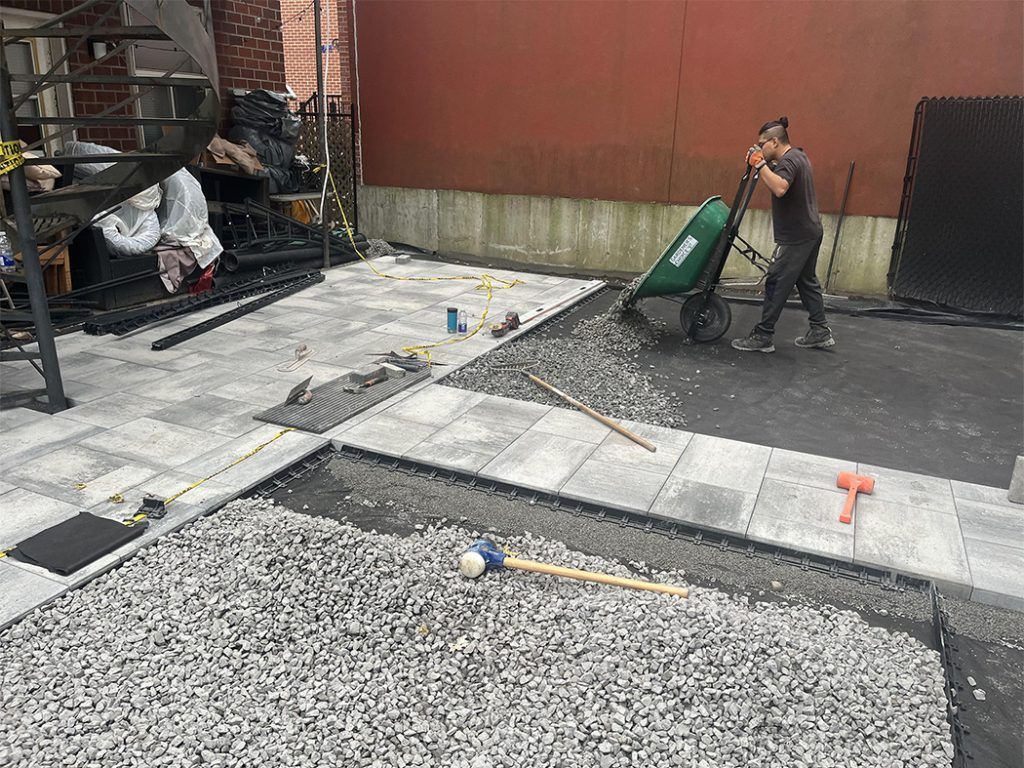 A man is pushing a wheelbarrow full of gravel.