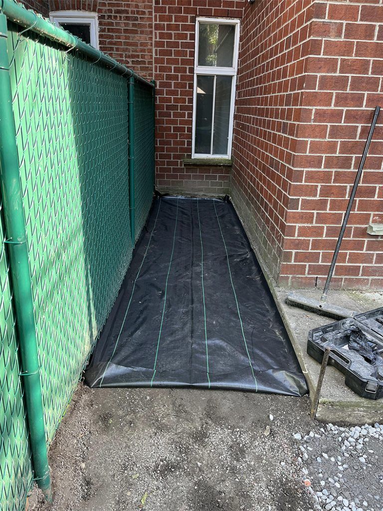 A black tarp is sitting on the ground in front of a brick building.