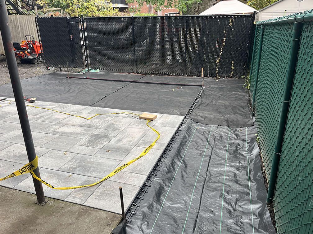 A backyard with a chain link fence and a patio being built.