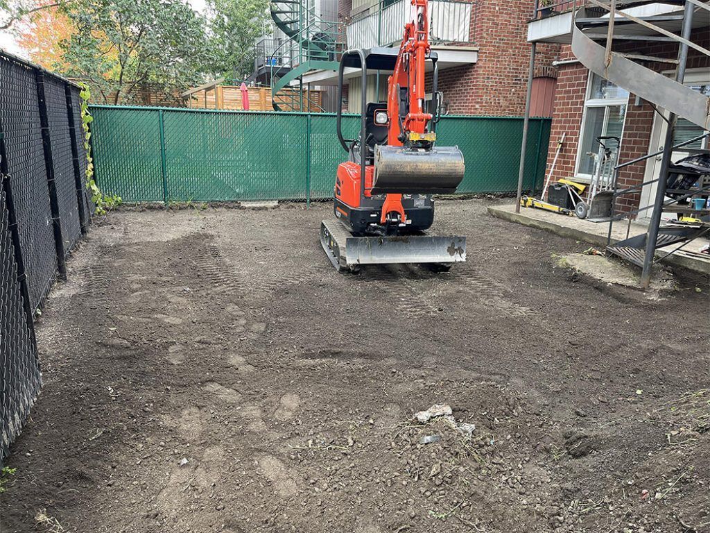 A small excavator is sitting on top of a dirt field.