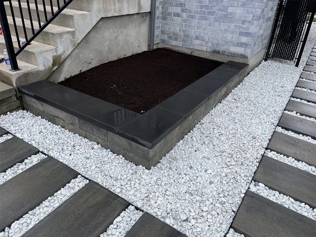 A concrete walkway with white gravel and a staircase in the background.