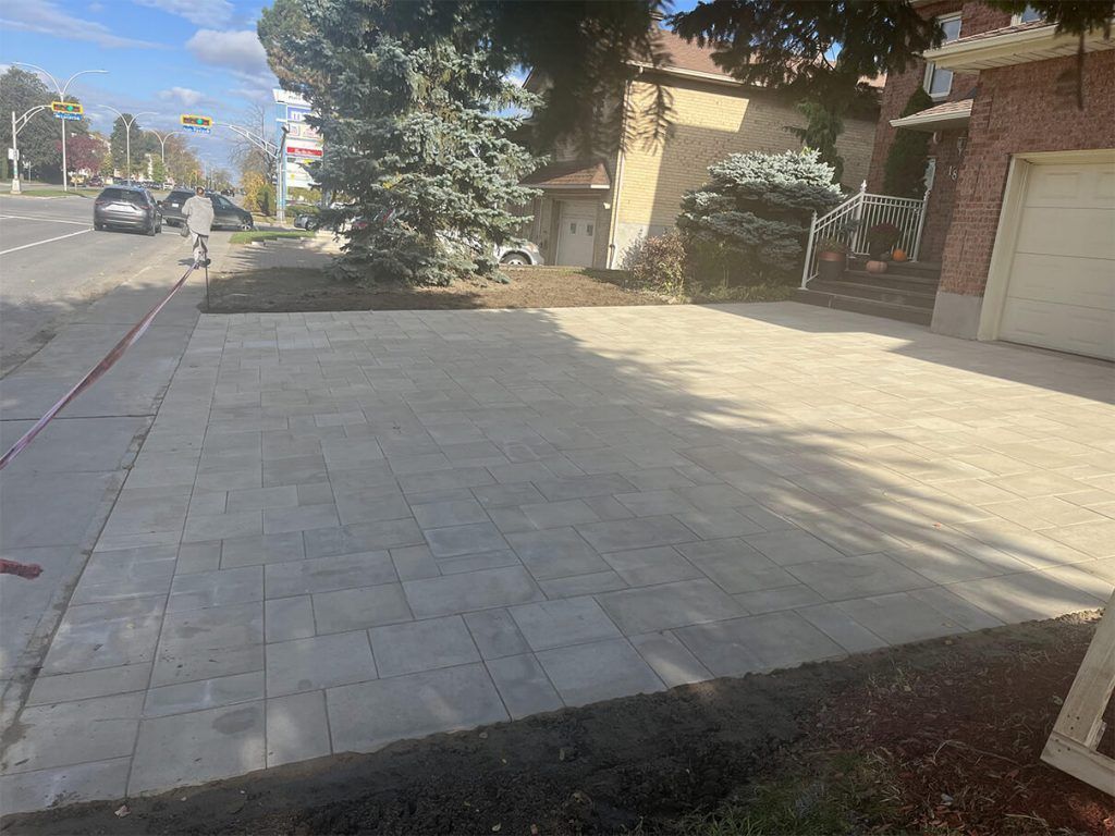 A brick driveway is being built in front of a house.