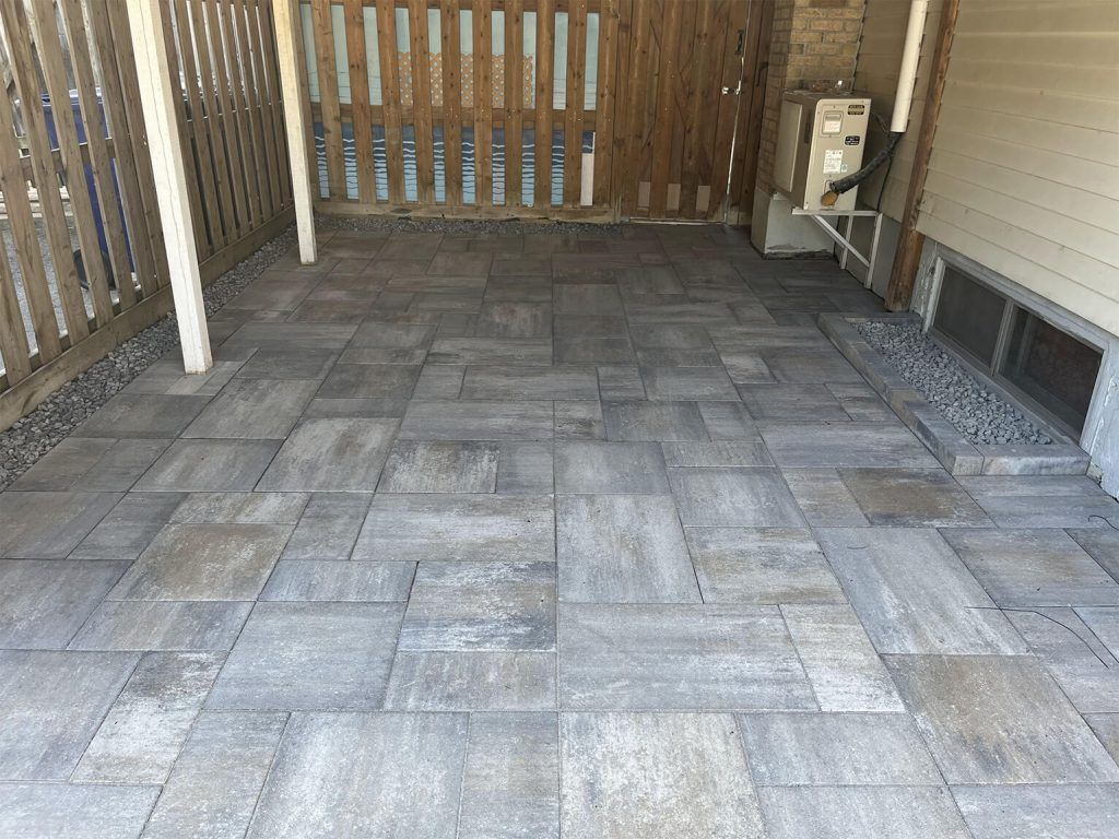 A patio with a wooden fence and a gray tile floor.