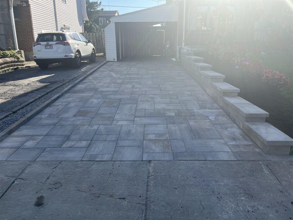 A white car is parked in a driveway next to a garage.