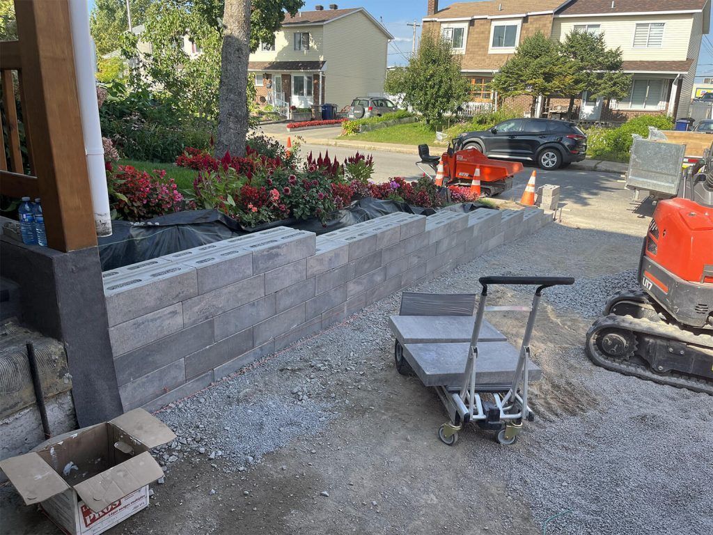 A cart is sitting on the ground in front of a brick wall.