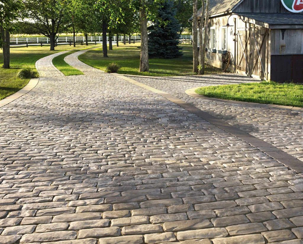 A cobblestone driveway leading to a garage and a house