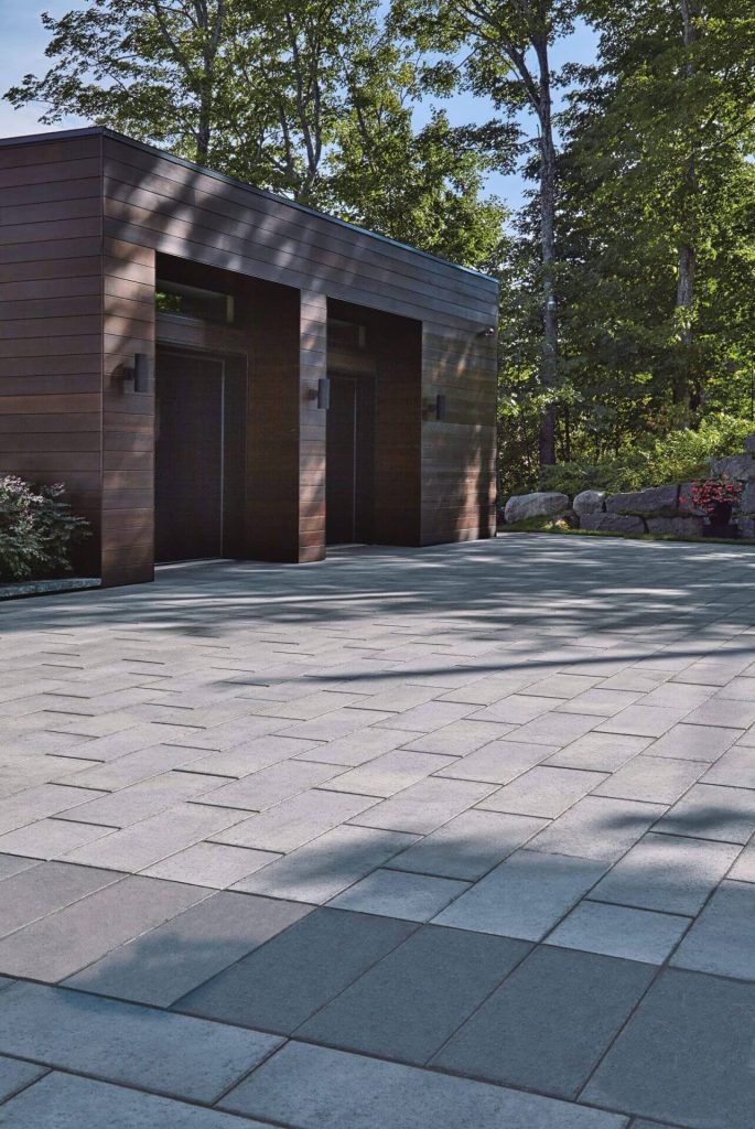 A driveway with a garage in the background and trees in the background.
