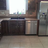 Modern kitchen with dark wood cabinets, stainless steel appliances, tiled backsplash, and a large window above the sink