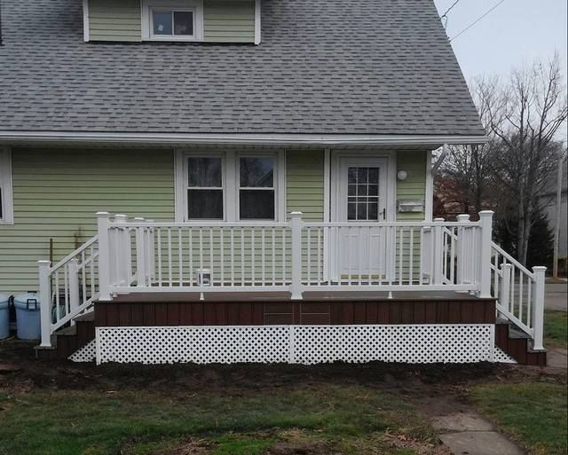 White-railed front porch with stairs on a green house, viewed from the yard