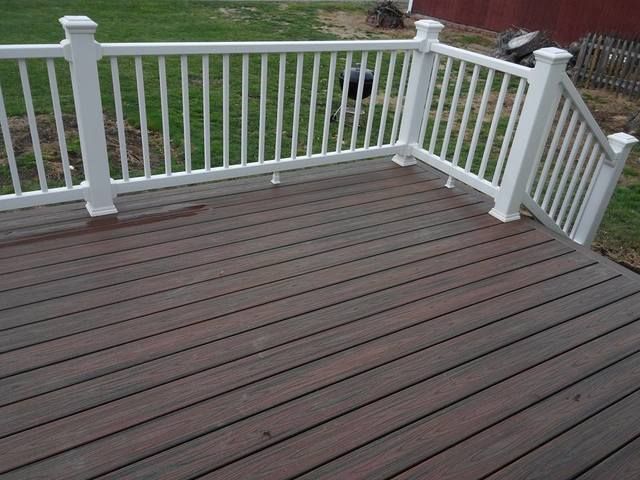 Wooden deck with white railings and steps overlooking a grassy yard