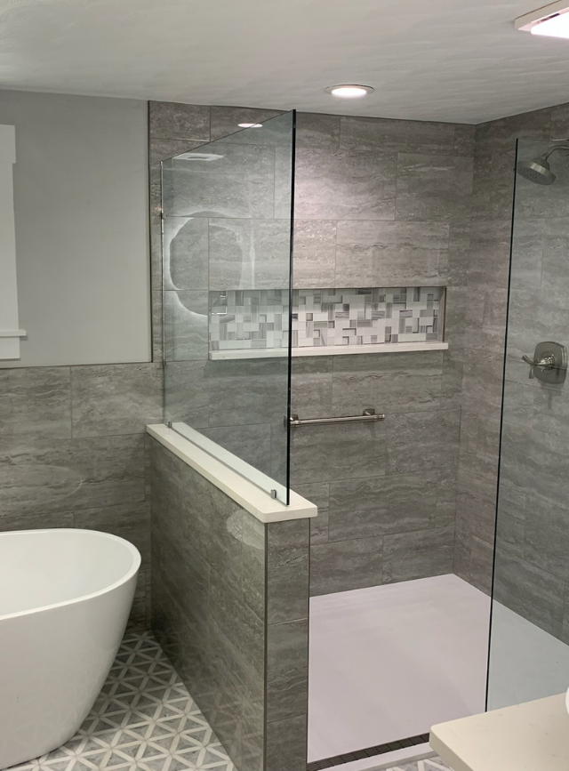 Modern gray-tiled bathroom with a glass walk-in shower and freestanding tub