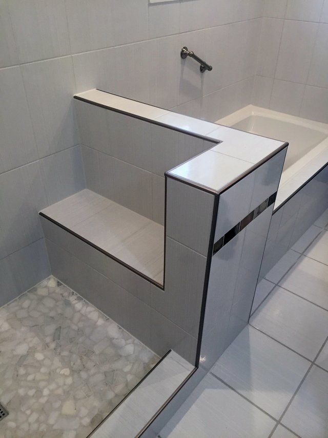 Accessible shower bench and grab bar in a tiled bathroom.