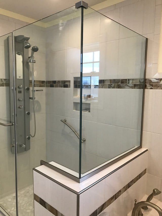 Glass walk-in shower with chrome fixtures and white tile walls