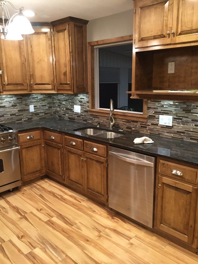 Wooden kitchen with granite counters, stainless steel appliances, and a window above the sink.