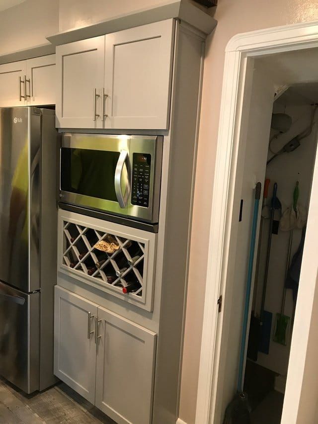 Built-in microwave and wine rack in a kitchen next to a pantry doorway