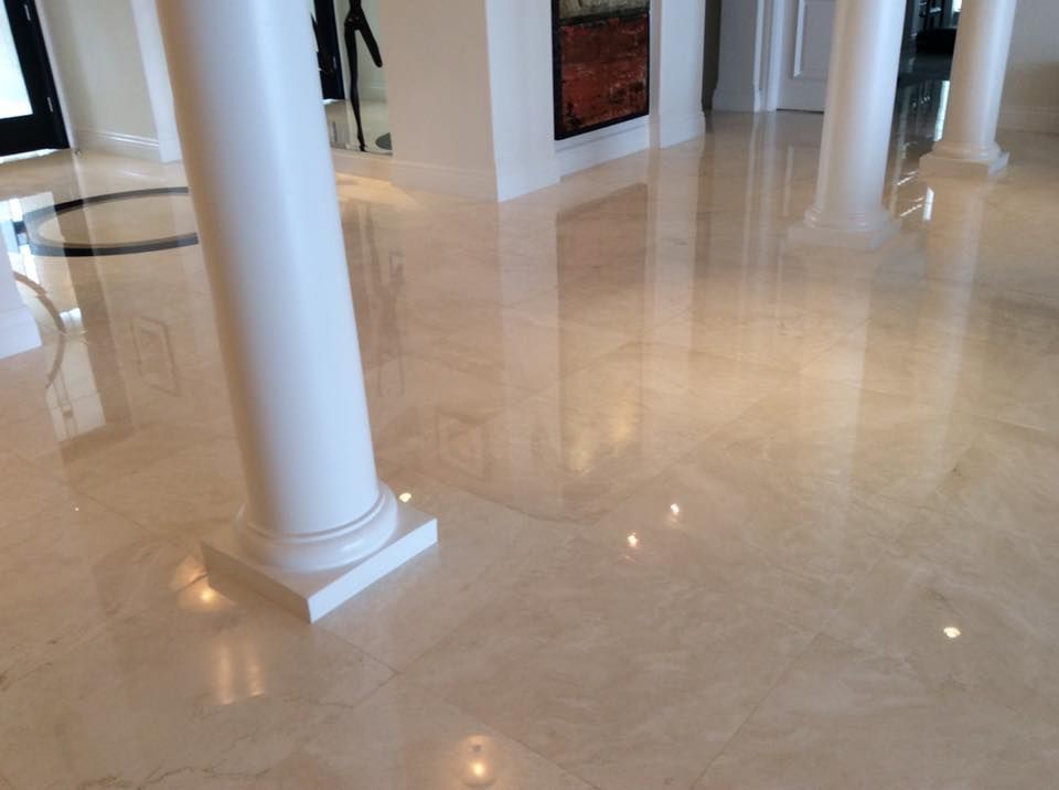 Polished beige marble floor reflecting white pillars in a bright interior.