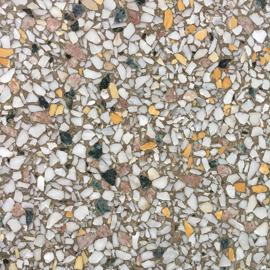 Close-up of terrazzo flooring with multicolored chips on a beige background.