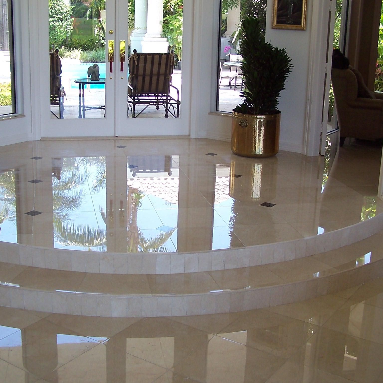 Polished marble floor with steps, leading to French doors overlooking a pool and patio furniture.