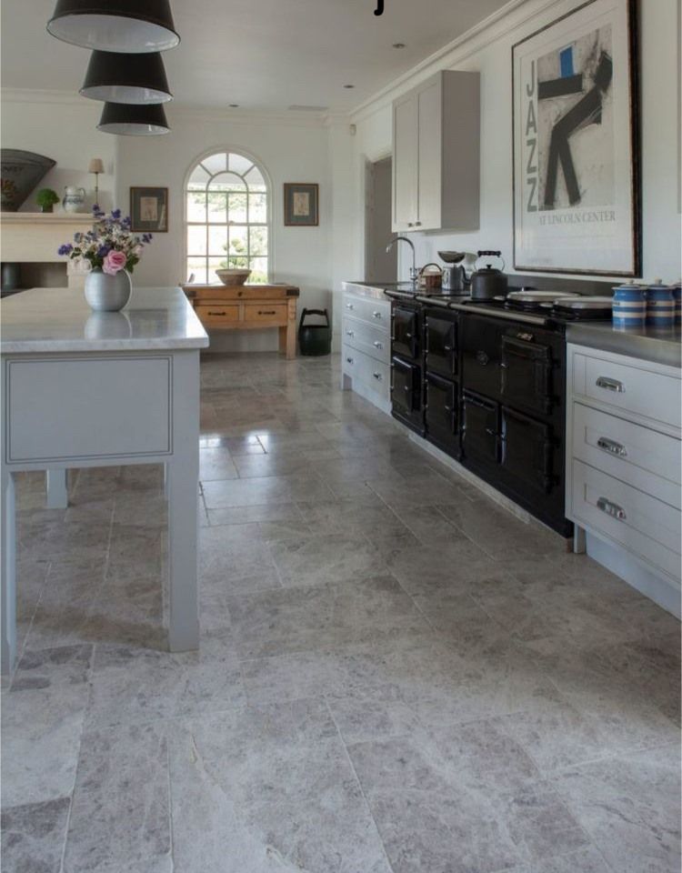 Kitchen with gray stone floor, white cabinets, black stove, and an island.