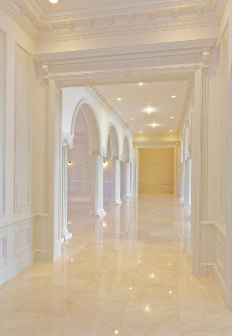 Elegant hallway with arched doorways, marble floor, and white walls.