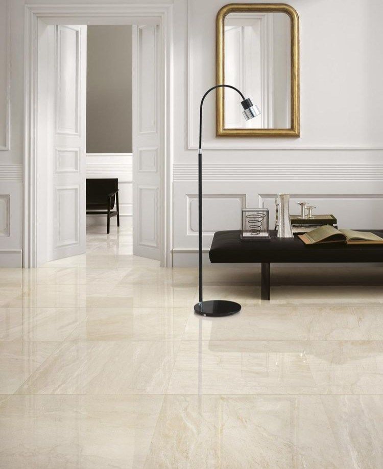 Elegant room with glossy beige tiled floor, white walls, arched lamp, and black bench with books.